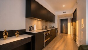 Une cuisine moderne avec des meubles de couleur sombre, des appareils électroménagers en acier inoxydable et un plancher en bois.