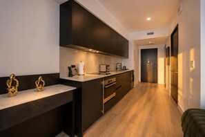 A modern kitchen with dark cabinetry, stainless steel appliances, and a wooden floor. - Exectutive E11EVEN Studio Suite with Elite Amenities (Miami)