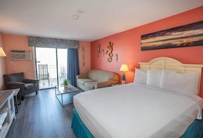 A hotel room with a bed, a sofa, a desk, and a balcony with a view. - Sea Mist 50810 Ocean View Escape (Myrtle Beach)