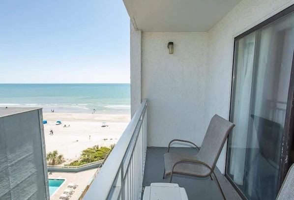 A balcony with a view of the beach, a chair, and a small table. - Sea Mist 50810 Ocean View Escape (Myrtle Beach)