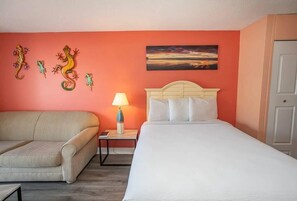 A hotel room with a bed, a sofa, a nightstand with a lamp, and a wall with decorative lizards. - Sea Mist 50810 Ocean View Escape (Myrtle Beach)