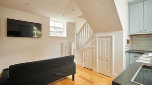A modern kitchen with a built-in island, white cabinetry, and a staircase leading to an upper level. - Host & Stay | The Spinney (Consett)