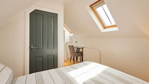 A bedroom with a bed, a desk, and a chair, a skylight, and a door. - Host & Stay | The Spinney (Consett)