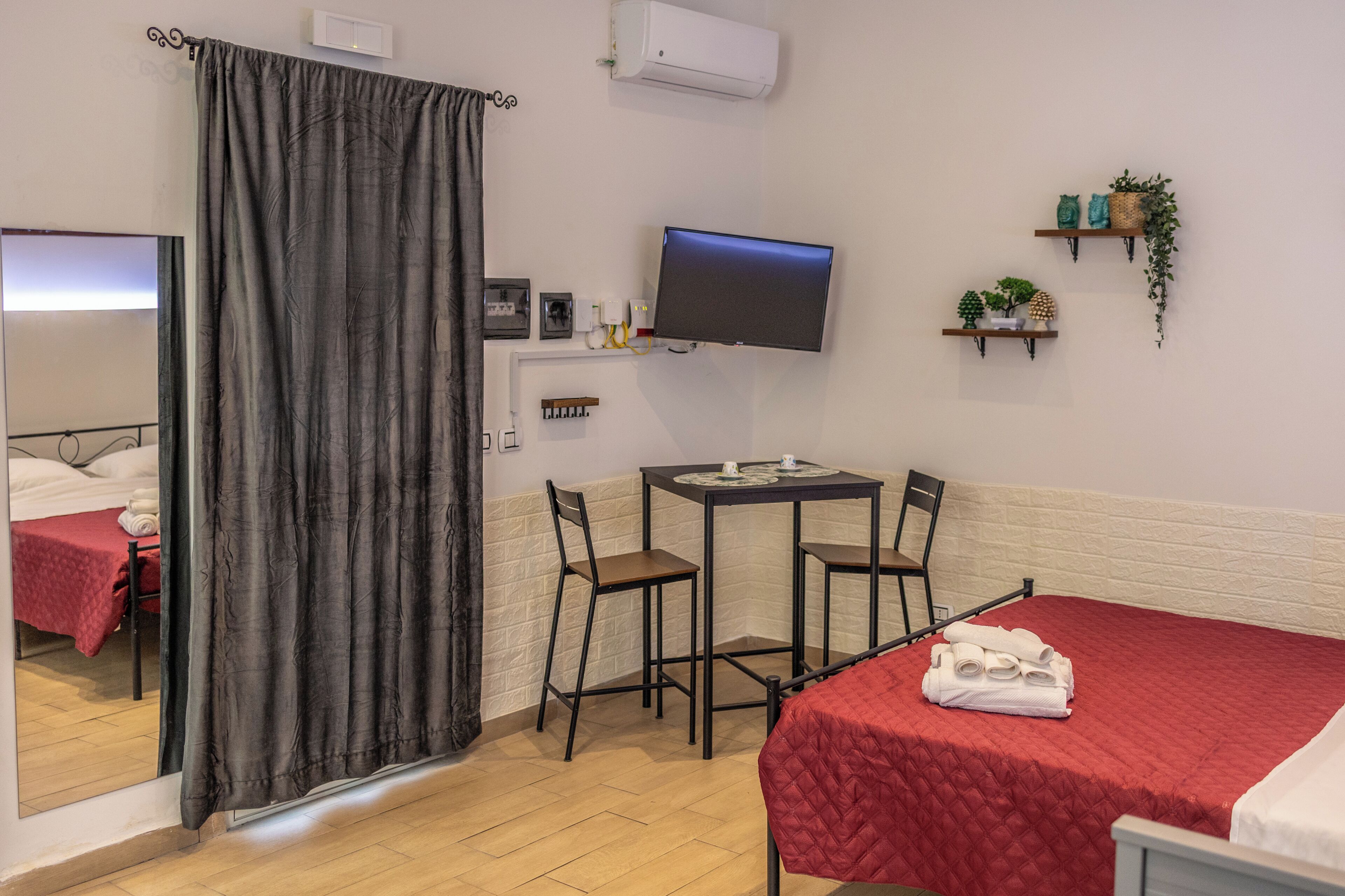 Une chambre d’hôtel comprenant un lit, un bureau avec une chaise, une télévision, un miroir et un rideau de douche.
