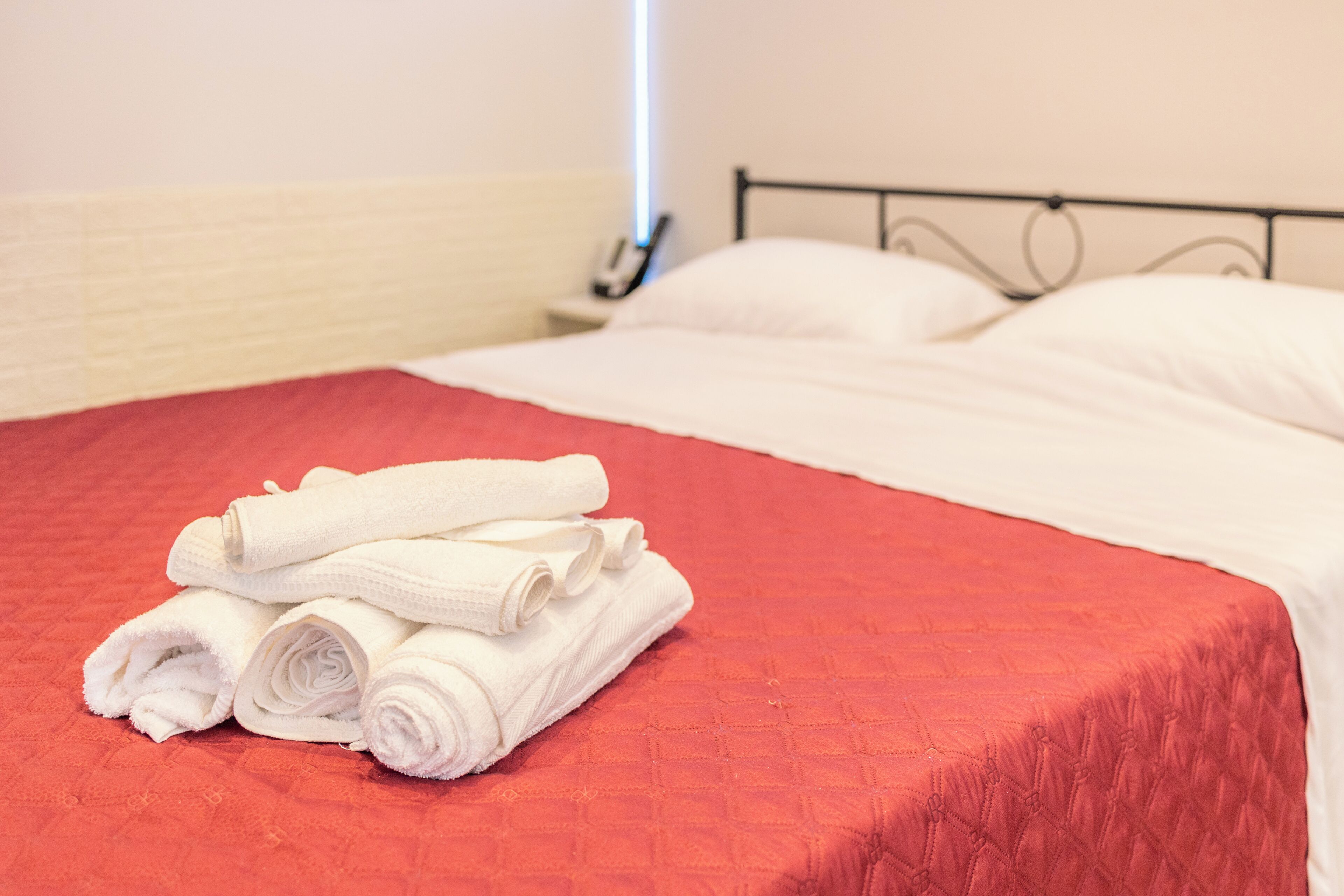 Una cama bien hecha con sábanas blancas y una colcha acolchada roja.