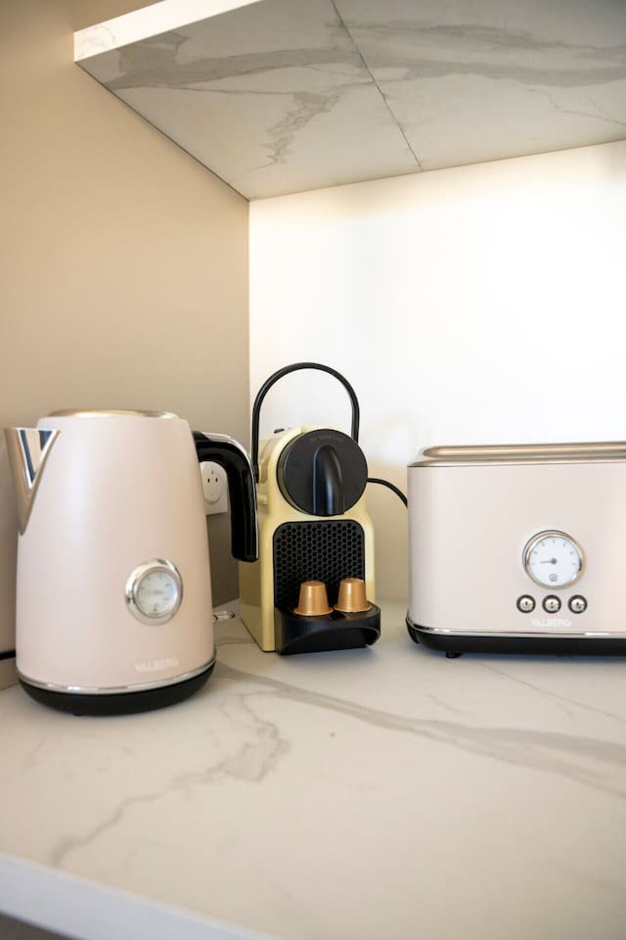 Un plan de travail de cuisine avec une machine à café, une bouilloire et un grille-pain.