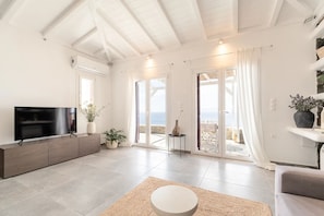 Una sala de estar moderna con un televisor de pantalla plana, un sofá, una mesa de centro y un balcón con vistas.
