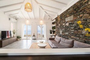 Una sala de estar moderna con una pared de piedra, un sofá, una mesa de centro y un televisor.