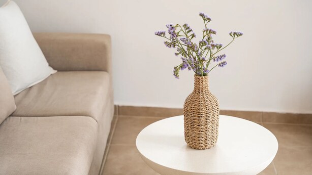 A round white table with a woven vase containing purple flowers.
