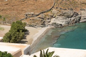Un paisaje costero con terreno rocoso, una playa y mar azul cristalino.