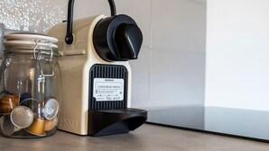 Une machine à café, un bocal rempli de capsules de café et un récipient en métal, le tout posé sur un plan de travail de cuisine.