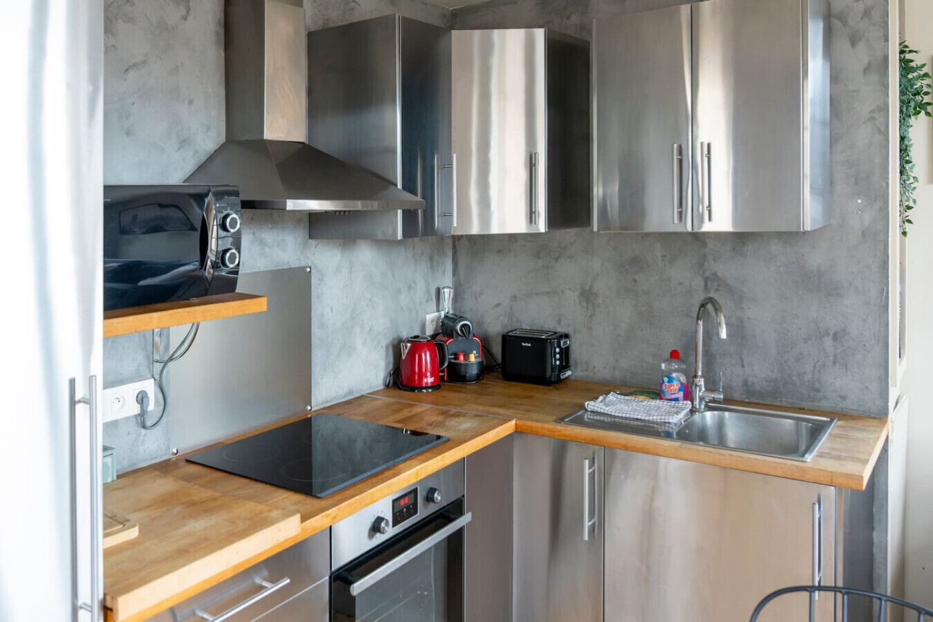 Una cucina compatta con elettrodomestici in acciaio inossidabile, un tostapane, un bollitore e un lavandino.