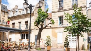 A street with buildings, a tree, and outdoor seating. - Apartment for 2, Place St. Sauveur (Caen)