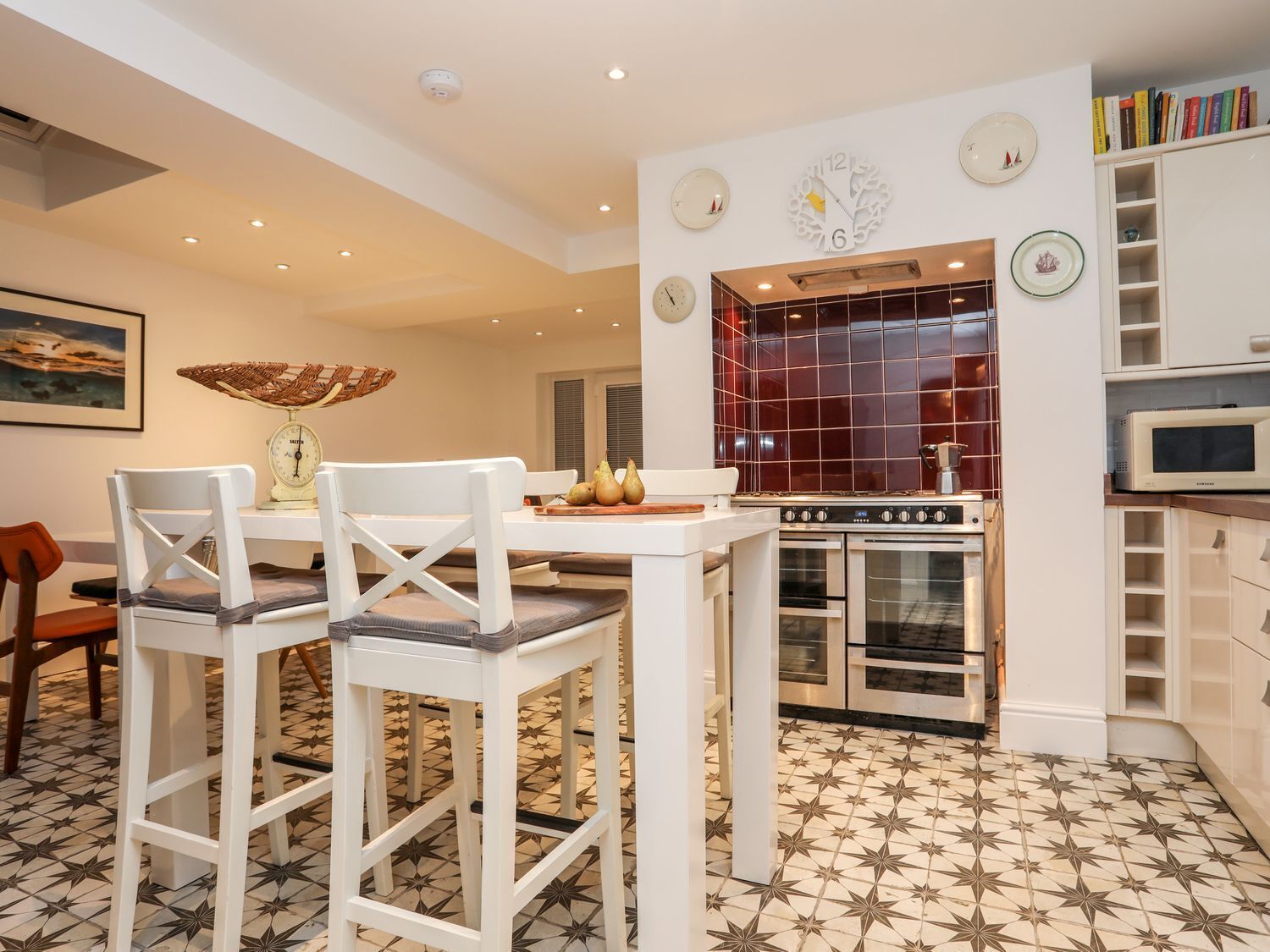 A modern kitchen with a dining area, featuring a white table, chairs, a stove, oven, and a microwave.
