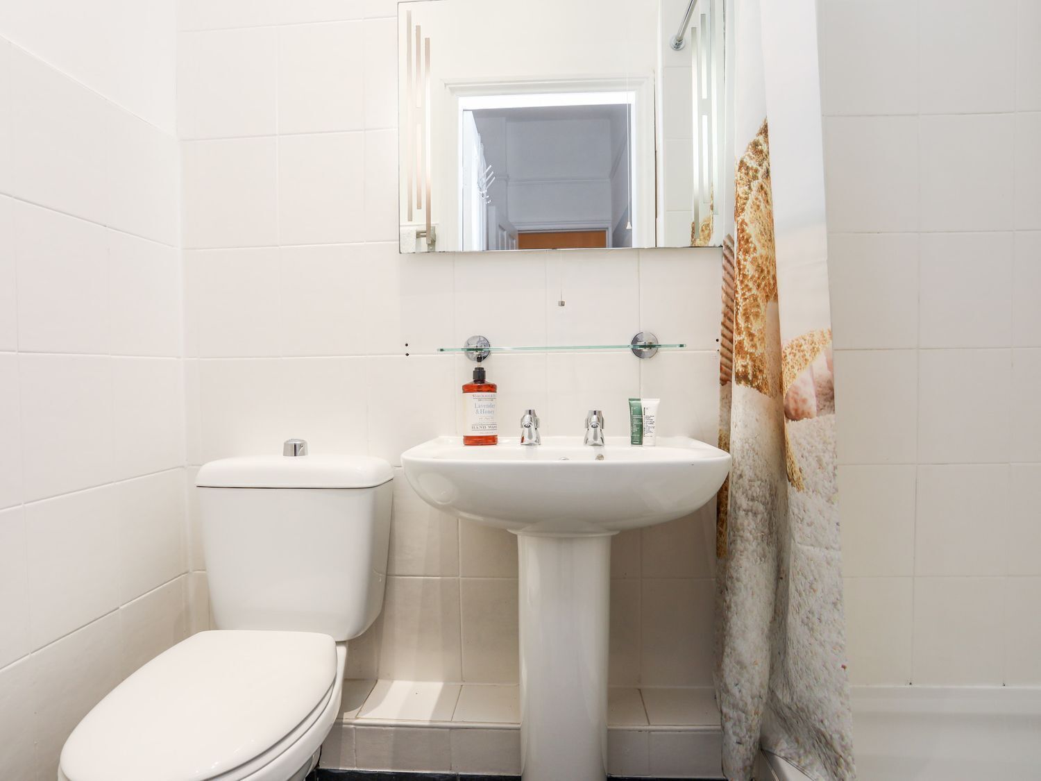 Ein Badezimmer mit Toilette, einem Waschbecken auf Säule und einem Spiegel darüber.