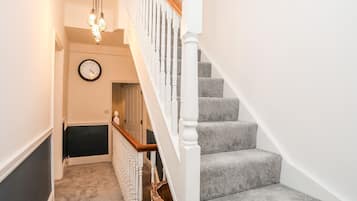 A staircase with grey carpeted steps, white balusters, and a wooden handrail.