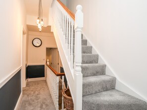 A staircase with grey carpeted steps, white balusters, and a wooden handrail. - Rhiwlas (Rhosneigr)