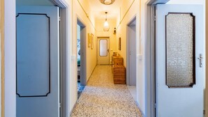 A hallway with a patterned floor, a hanging light fixture, and a door with a textured panel. - A charming 90-square-meter villa, perfect for six guests, featuring a private street-level entrance.The property is situated in a quiet area of ​​Silvi and enjoys a great location: thanks to a pedestrian path, you can reach the sea in just 10 minutes (Silvi)