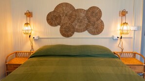 A room with a bed, two wicker chairs, a wall-mounted circular decorative piece, and two wall-mounted lamps. - A charming 90-square-meter villa, perfect for six guests, featuring a private street-level entrance.The property is situated in a quiet area of ​​Silvi and enjoys a great location: thanks to a pedestrian path, you can reach the sea in just 10 minutes (Silvi)