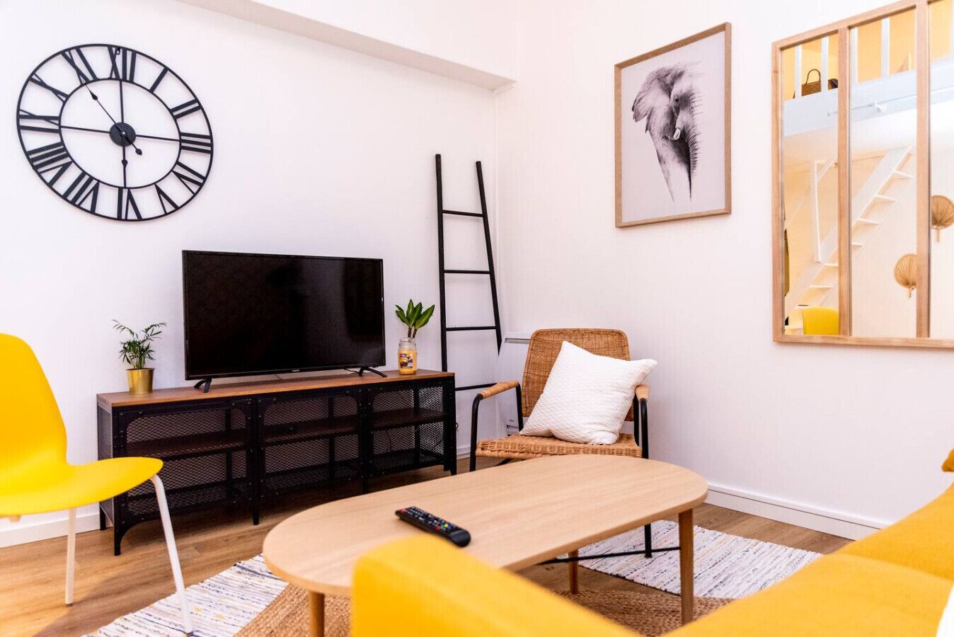 A living room with a TV, a clock, a ladder, and a framed picture on the wall.