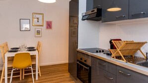 Een kleine keuken met een eettafel, stoelen en een hanglamp.