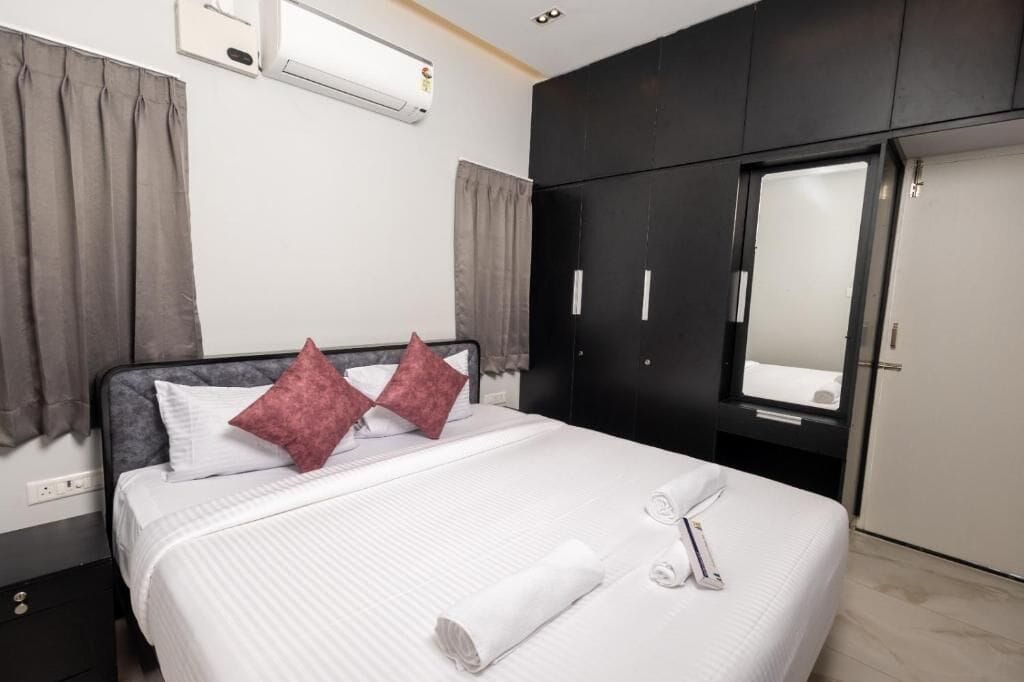 Une chambre d’hôtel équipée d’un lit, d’une armoire, d’un miroir et d’un appareil de climatisation.
