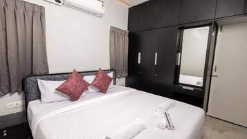 Une chambre d’hôtel équipée d’un lit, d’une armoire, d’un miroir et d’un appareil de climatisation.