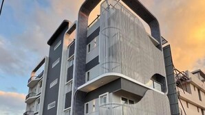 Un edificio moderno de varios pisos con balcones, fachada curva y entrada protegida.