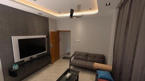Una sala moderna con televisor de pantalla plana, un sofá, una mesa de centro y un ventilador de techo.