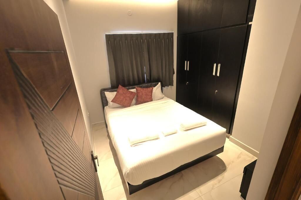 Een slaapkamer met een bed, hoofdeinde, kast en een deur.