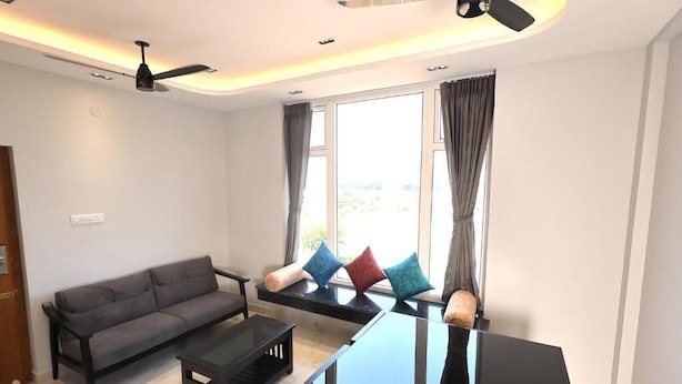 Una sala de estar moderna con un sofá, una mesa de centro de vidrio y un ventilador de techo.