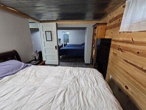 Ein Schlafzimmer mit Bett, Kleiderschrank, einer Tür zu einem anderen Raum und einem Fernseher.