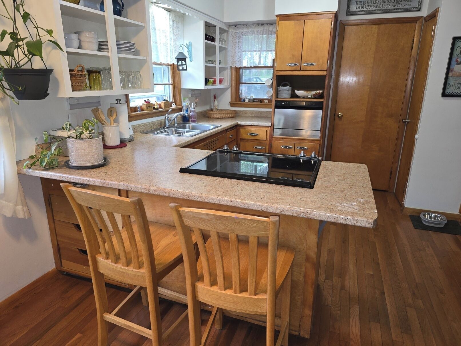 A kitchen with a central island, wooden chairs, and built-in cabinets.