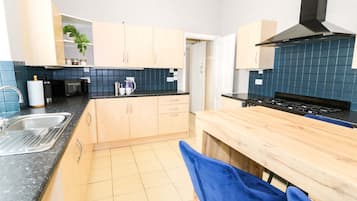 A modern kitchen with light wooden cabinets, a black stove, and a blue tiled backsplash.