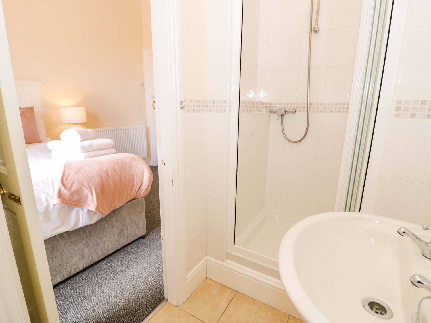 Habitación de hotel con cama, ducha y lavabo.