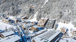 Een besneeuwd dorp met moderne gebouwen, een skilift en een berg op de achtergrond.