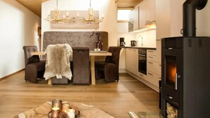 Een gezellige woonkamer met een open haard, een eethoek met een bont plaid, en een keuken met moderne apparaten.