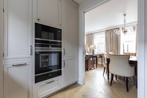 A modern kitchen with white cabinetry, a built-in oven, and a dining area with a chandelier. - Brunswick Mews II - Two Bedroom House, Sleeps 4 (London)