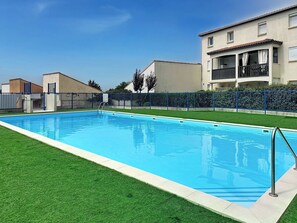 A rectangular swimming pool with a metal ladder, surrounded by a blue fence and a well-maintained lawn. - Port Saint-Jacques by Interhome (La Bernerie-en Retz)