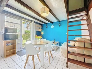 Een moderne keuken met een magnetron, een eethoek met een tafel en stoelen, en een blauwe accentmuur.