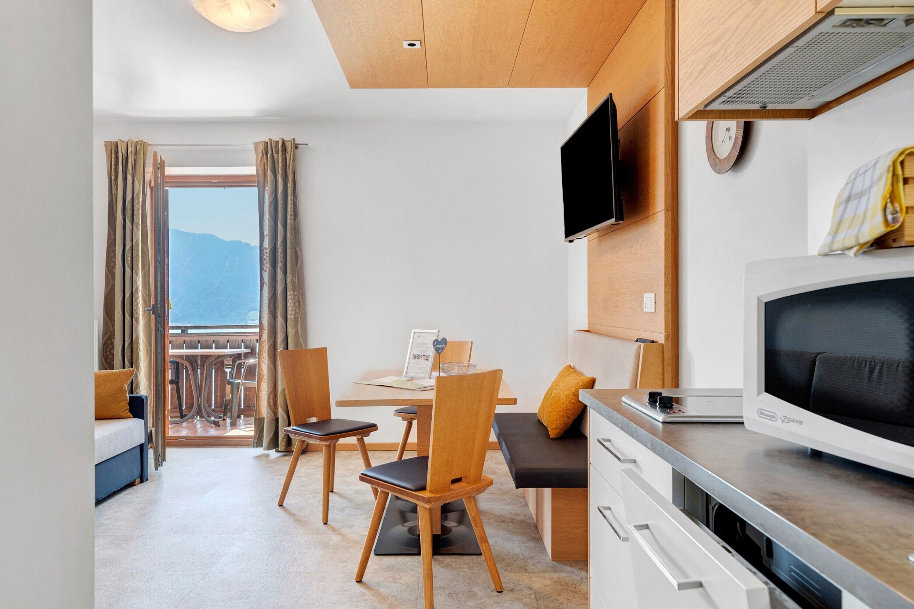 Une chambre d’hôtel moderne dotée d’un coin repas, d’une télévision et d’un balcon avec vue.