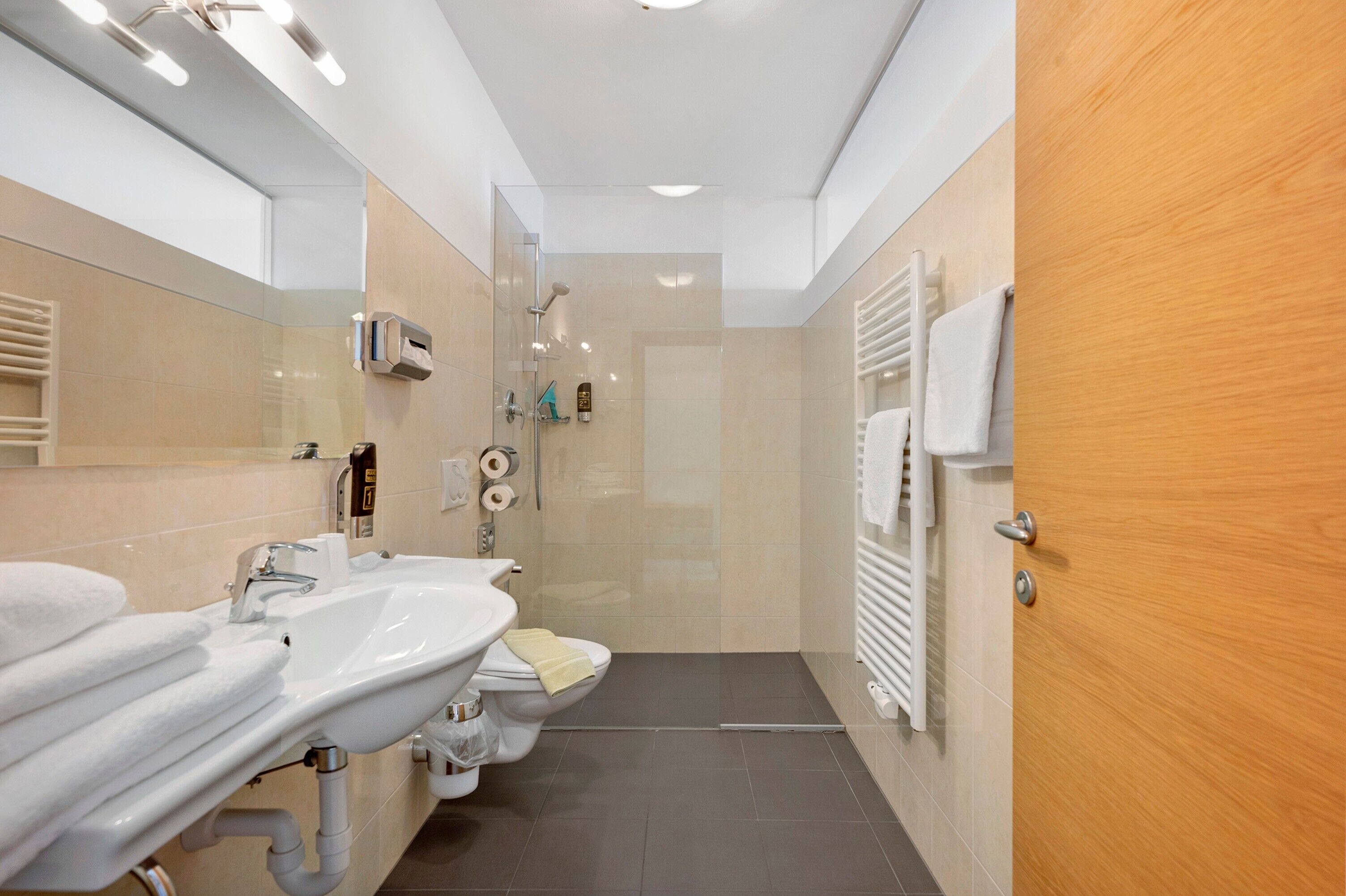 Ein modernes Badezimmer mit Waschbecken, Spiegel, Toilette und Dusche.