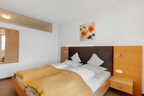 Una habitación de hotel con cama, mesita de noche y un cuadro en la pared.
