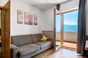 Una habitación con sofá, radiador y vista al mar a través de un ventanal.