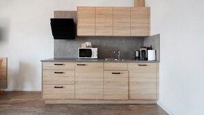 Una cocina moderna con armarios de madera, microondas, lavamanos y cafetera.