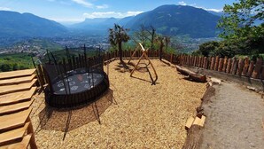 Una vista elevada de un valle, una terraza de madera, un área de estar circular y una valla de madera.