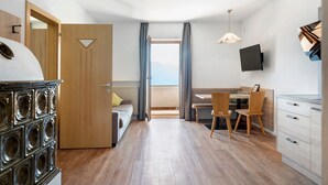 Habitación de hotel moderna con piso de madera, una cama, un escritorio con silla, televisor montado en la pared y vista a las montañas por la ventana.