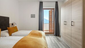 Habitación de hotel con cama, armario y vista a través de una ventana con cortinas.