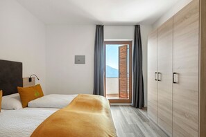 Habitación de hotel con cama, armario y vista a través de una ventana con cortinas.