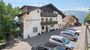 Un hôtel à la façade blanche, doté de balcons en bois et surplombant un paysage montagneux.